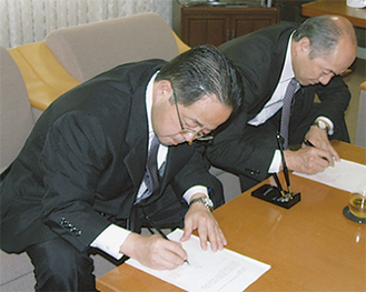 服部市長（左）と木村町長が協議書に調印した