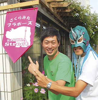 長谷川さん（左）とイベントに登場するという「さくらマスク」（右）。参加店舗は軒先のフラッグが目印