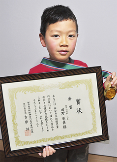 ２つの予選で獲得したメダルと賞状を両手に持ち喜ぶ田野君（上）と受賞作「ひまわりアスレチック」（下）