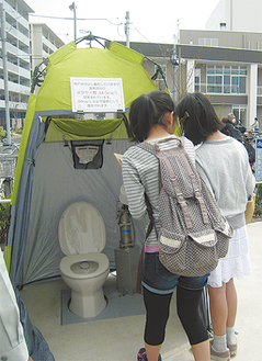 駐輪場に設置された災害用水洗トイレを体験する参加者ら