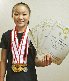 ６個のメダルと賞状を手にする川野さん