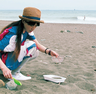 作品で使用する砂を茅ヶ崎海岸で採取する若見さん