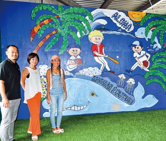 「大きな壁を見てクジラを描きたいと思った」と佐々木さん（右）、「イメージ通りで子どもたちも喜ぶ」小野オーナー(左)と、ピラティスを教える松本純子さん