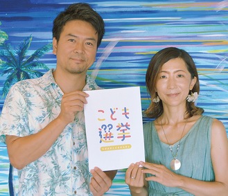 こども選挙のロゴを手にする池田さん夫妻