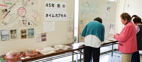 展示されている寄せ書きや写真に懐かしそうに目をやる来場者＝22日、小出地区コミュニティセンターのロビー