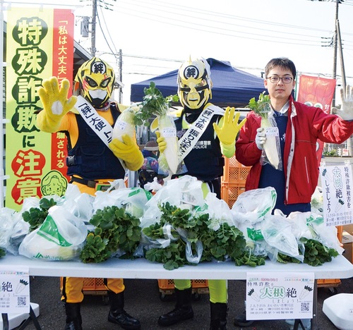 「絆」大使トラセンジャー（左）と振り込まセンジャー（中央）、山積みの大根で「大根絶」を訴えた