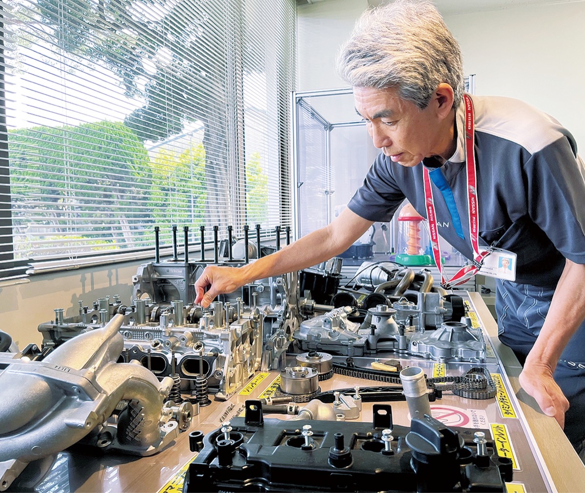 分解されたエンジンの部品を説明する福田さん