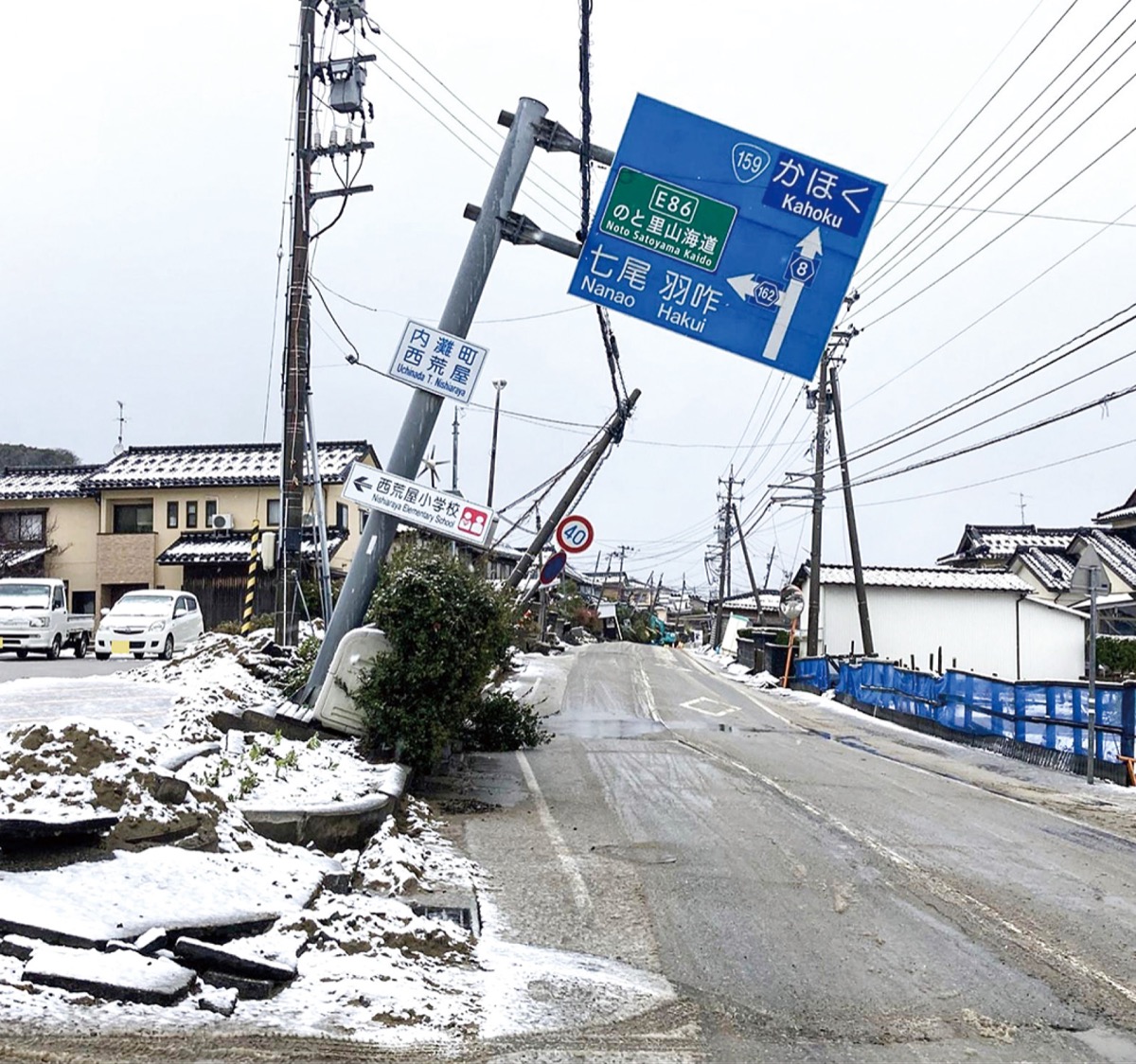 傾いた西荒屋小学校前の道路標識＝２０２４年1月13日撮影、内灘町