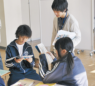 学生が教員の補佐として授業を手伝う。写真は会話形式で英語の教科書を読み合う生徒をチェックする佐々木さん(中央)。