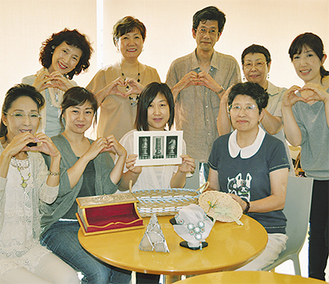湘南クリエイターズプロジェクトのメンバー（下段中央が大宮さん）合言葉は「絆」手でハートマークを作り、カメラに笑顔を向ける