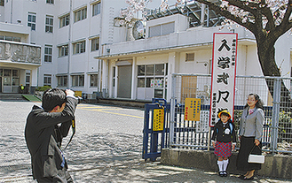 小学校の正門前で記念撮影する家族