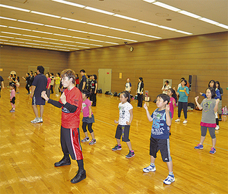 リーダーのTATSUさん（写真左手前）からダンスの指導を受ける参加者。手話や踊りの経験がない人も多い
