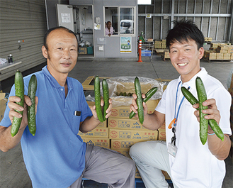 鮮度自慢の湘南キュウリを手にする吉川さん（左）とＪＡ湘南職員（右）