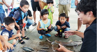 定置網で獲れた魚の説明を受ける子供たち