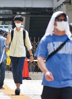 扇子や手拭いで暑さをしのぐ歩行者（22日午前11時39分、平塚駅周辺）