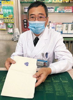県薬剤師会が制作したブラウンバッグを手にして残薬回収を呼びかける今井会長
