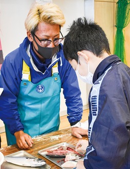 魚を触る児童と進藤さん(左)