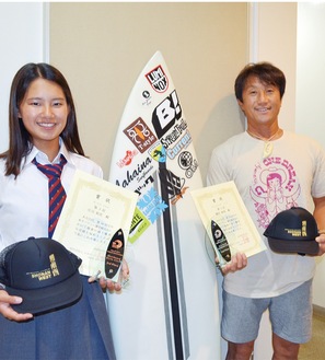 全日本サーフィン選手権大会で３位入賞した庄司さん（左）と準優勝した磯部さん。賞状と盾のほか、スポンサー企業から送られた湘南西支部のキャップを持っている