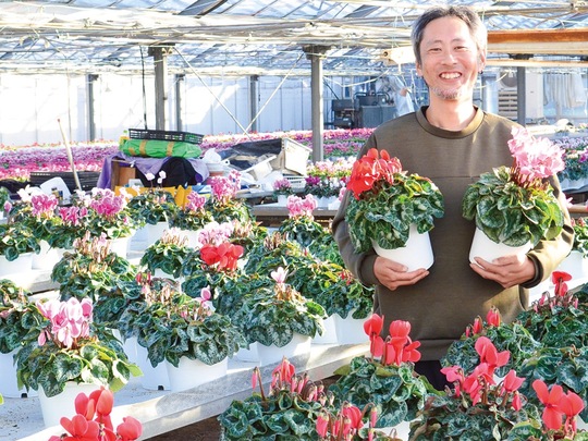 自慢のシクラメンを手に笑顔の雅幸さん（12月６日撮影）