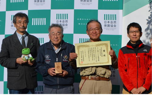 賞状を手に喜ぶ臼井理事長（右から２人目）