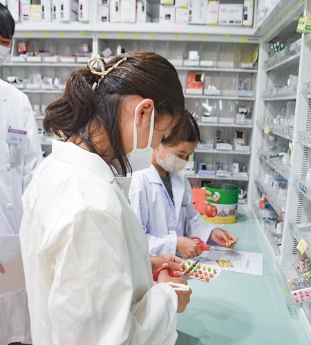 錠剤に見立てたチョコレートを慎重に調剤する参加児童ら