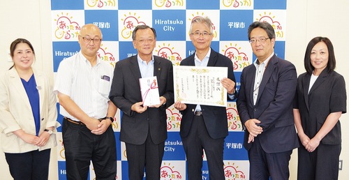 感謝状を持つ田村社長と目録を持つ落合市長ら