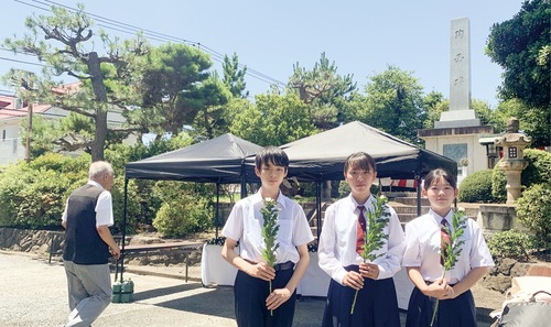 殉国碑前に立つ（左から）黒田さん、山下さん、秋元さん