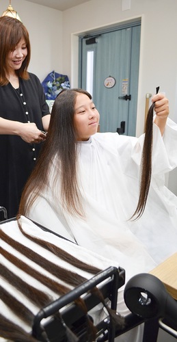 寄付する自らの髪の毛を手にする古橋さん（右）と美容師の宮崎さん