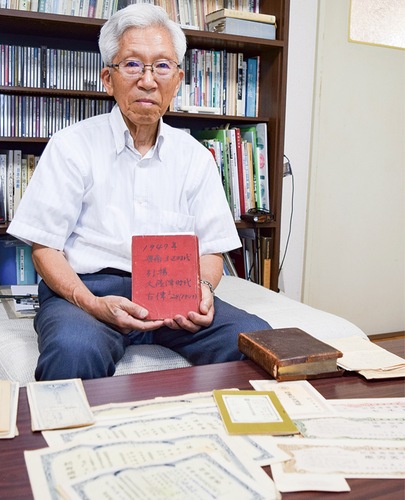 母の日記や｢引揚者国庫債券｣を手に取材を受ける中村さん