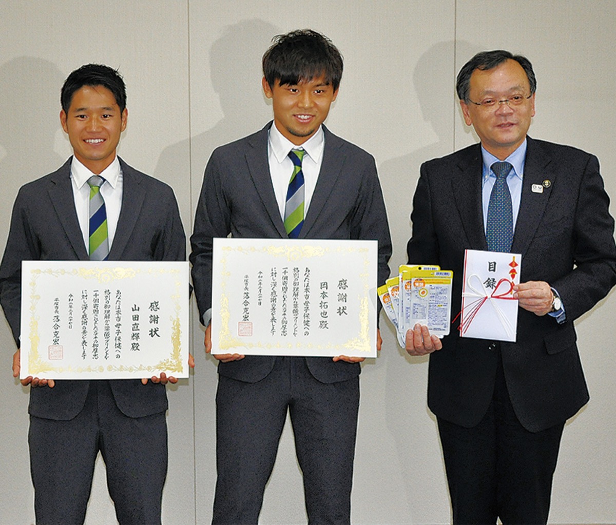落合市長に目録を手渡した山田選手(左)と岡本選手