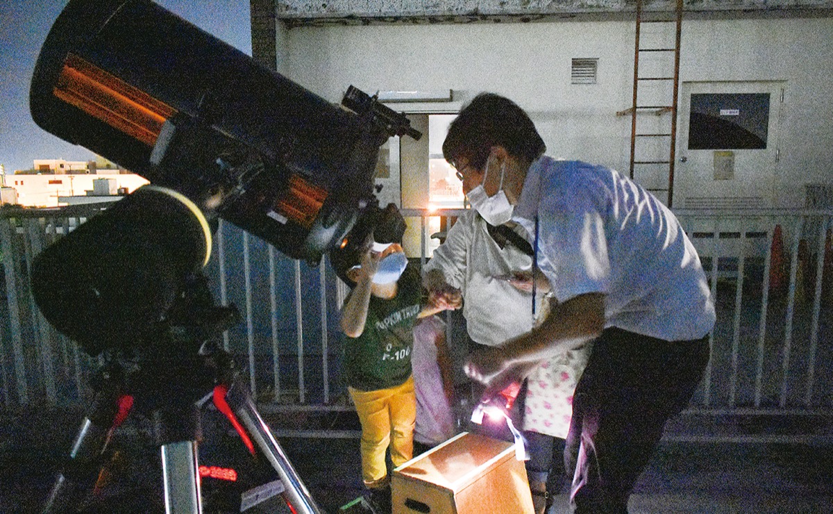 学芸員と一緒に望遠鏡をのぞく親子