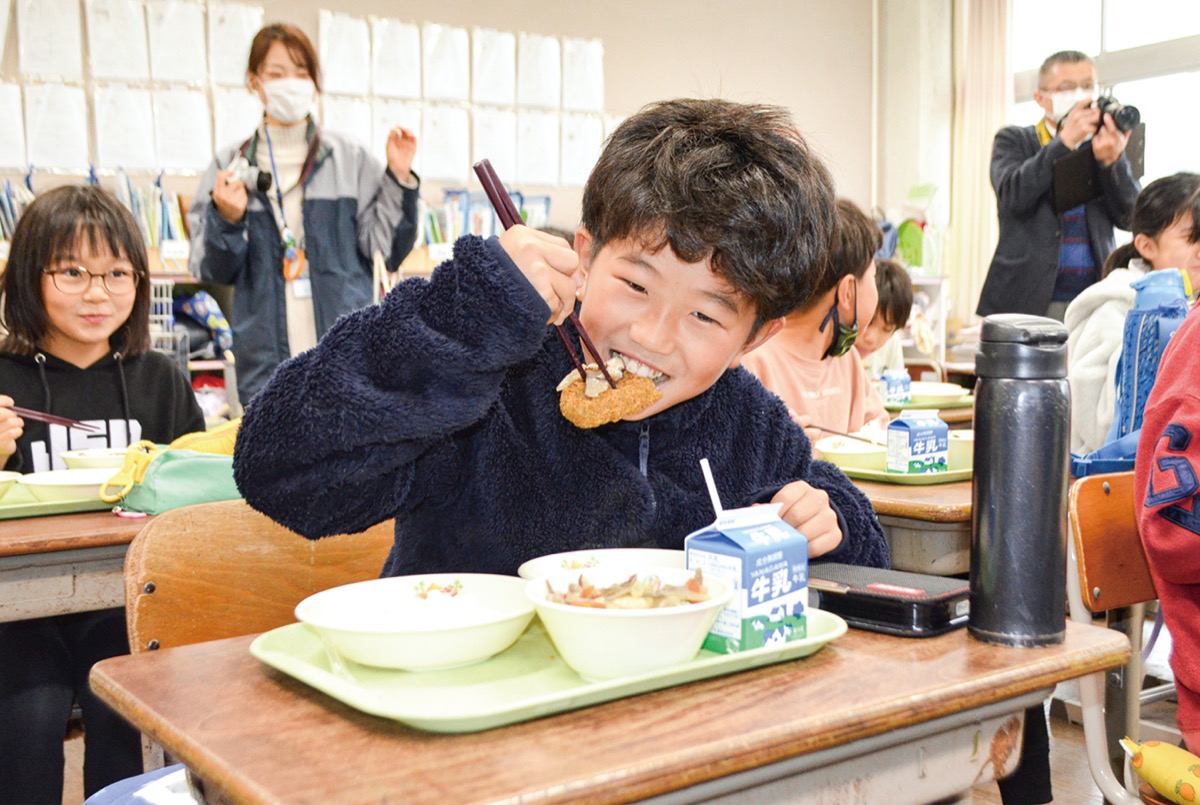 交流給食を笑顔で食べる児童(4年生)