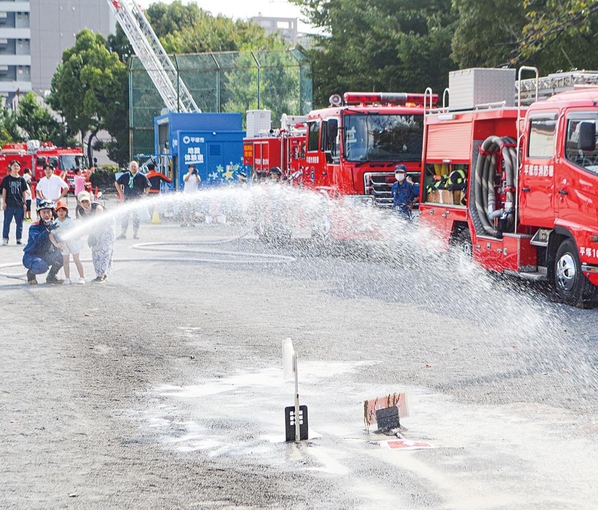火元に見立てた的に向かって消火活動の体験をする参加者親子
