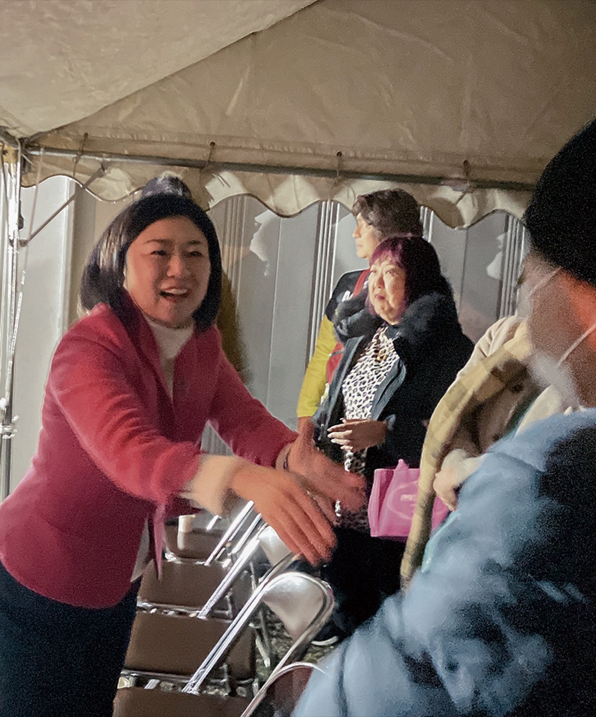 当選を喜ぶ支援者と手を取り合う牧島氏（８日、事務所前で）