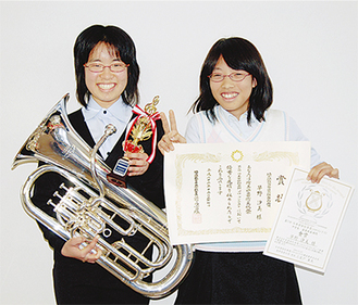 トロフィーと楽器のユーフォニアムを手にする早野汐美さん（写真左）と、ピアノ伴奏をした松田美紗さん（写真右）