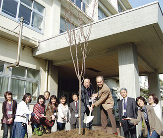 桜の苗木を植える保護者と教職員。スコップを持っているのが鈴木校長（左側）と小嶋ＰＴＡ会長