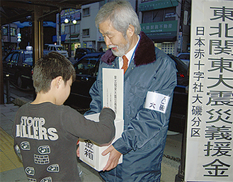 中崎町長（右側）も呼びかけた街頭募金で小銭を寄付する小学生