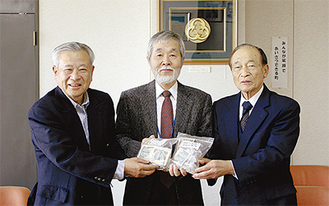 中崎町長へ義援金を手渡す関威國さん（写真左側）と伊勢田七良さん（右側）