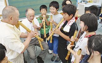 高橋昭一さん（写真左端）の指導で尺八の吹き方を学ぶ６年生たちと小林校長