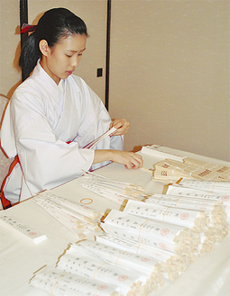 長寿箸を袋に入れる六所神社の巫女
