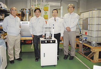 開発にあたった（写真左から）荒木豊昭さん、花牟礼研一さん、久米社長、大松真朋さん。手前の装置が研究開発用ナノバブル生成装置。右端に見えるのは１ｔの『根活』が作れる大型製造機