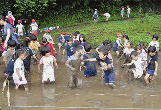 雨の中で泥遊びに興じる子どもたち
