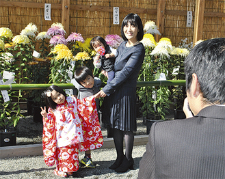大輪の菊を背景に記念撮影をする家族