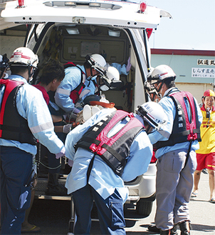 要救護者を救急車へ運ぶ救急隊員たち＝大磯漁港