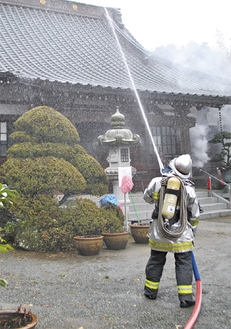 本堂の屋根に向けて放水する消防隊員