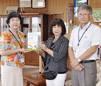 絵本『コインでつなぐ平和の鐘』を手にする相沢さん（写真中央）と村田町長。右は府川教育長
