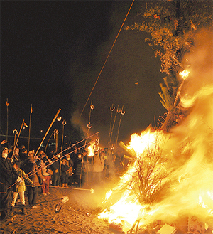燃え盛る火で団子を焼く町民ら