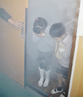 疑似煙の中で避難訓練をする園児