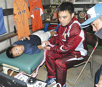 エコー検査を行う吉田院長（中央）。選手の父親（右）も同席し、子どもの肘の状態を確認した