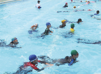 服と運動靴を身に着けて泳ぐ児童